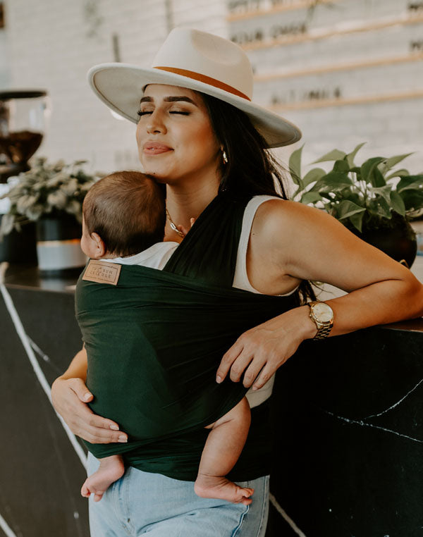 hispanic woman in baby wrap carrier with gigipip hat at a local coffee shop with newborn baby